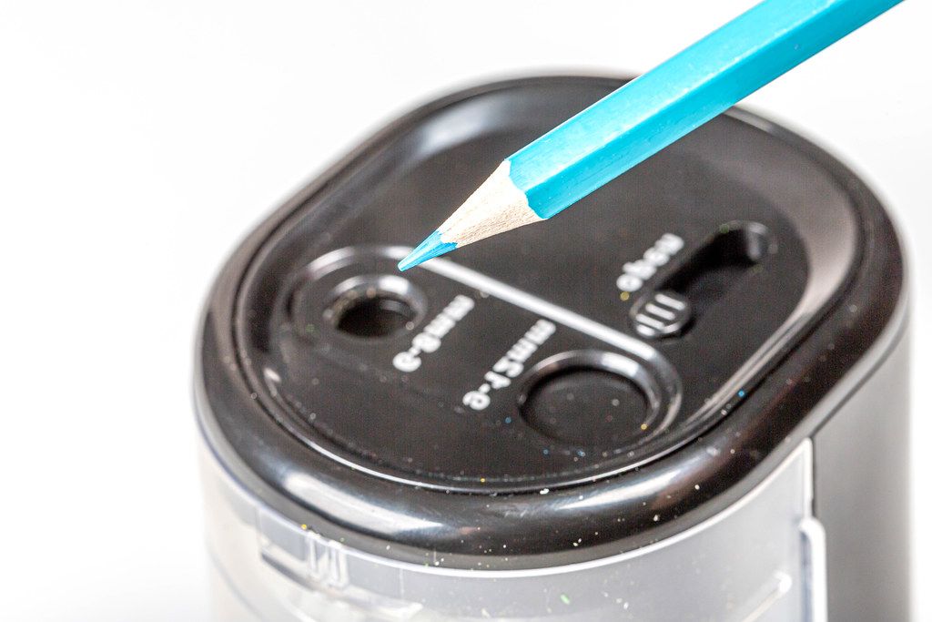 Close-up electric black sharpener with blue pencil (Flip 2020)