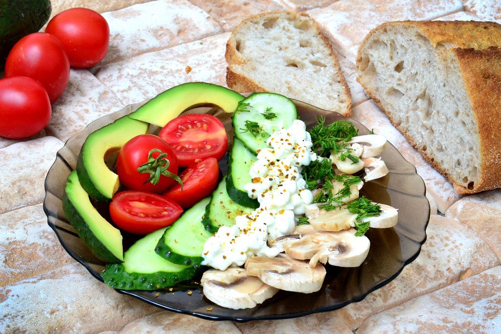 Close Up Food Photo of Healthy Plate with Avocado, Cherry Tomatoes, Cucumber, Mushrooms and Fresh Bread