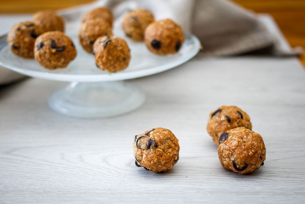 Close Up Food Photo of Oatmeal Energy Balls with Chocolate Chips on a White Wooden Table