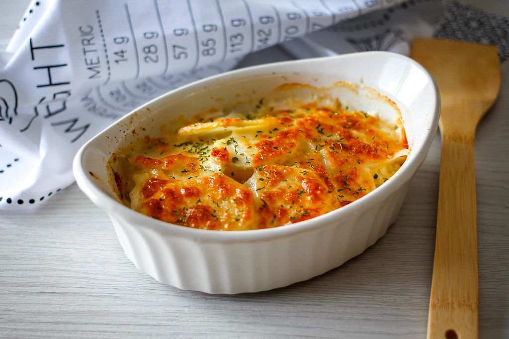Close Up Food Photo of Potato Gratin with Cheese in Ceramic Baking Bowl on Wooden Table