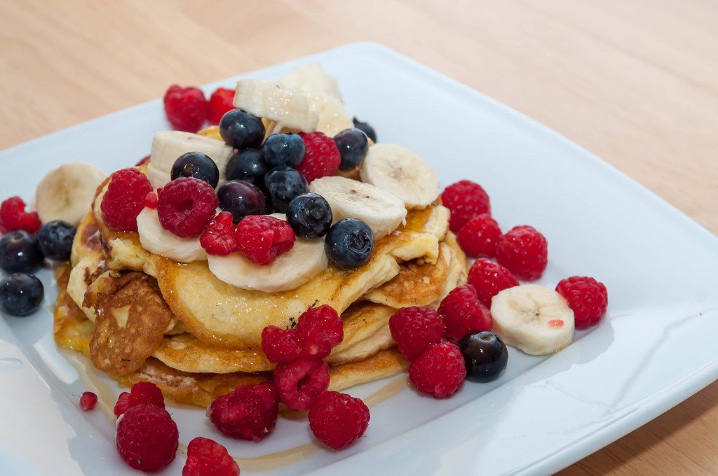 Close Up Food Photo of Protein Pancakes with Berries and Honey on a White Plate
