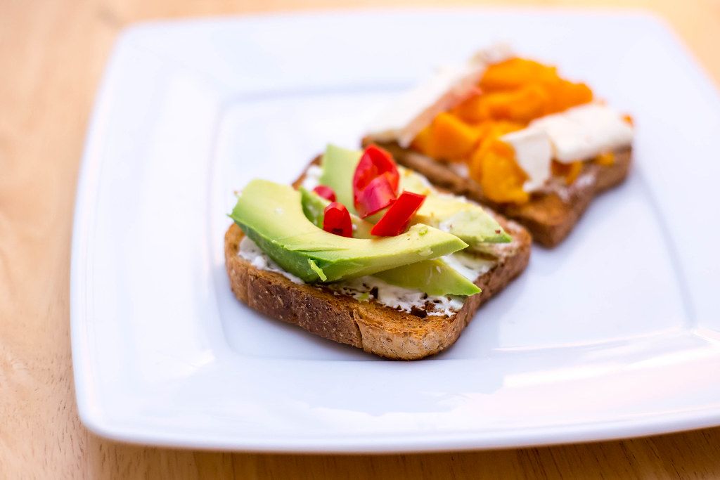 Close Up Food Photo of Toast with Cream Cheese, Avocado and Chili on White Plate
