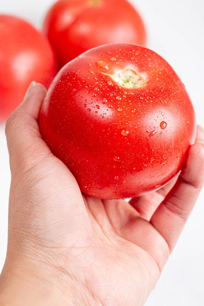 Close-up, fresh red tomato in a woman's hand
