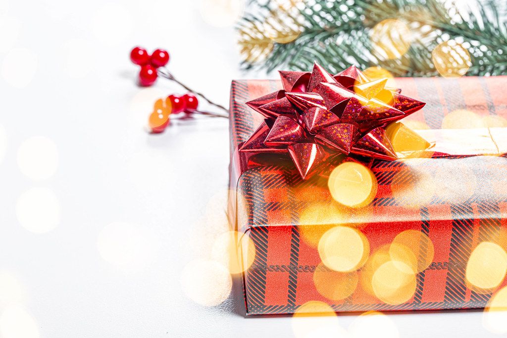 Close-up gift in red packaging with yellow bokeh. The concept of surprise for loved ones