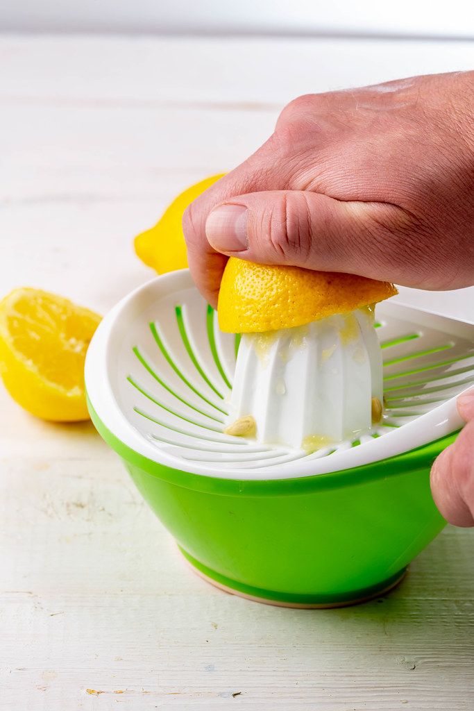 Close-up of a man squeezes juice from a lemon using a hand juicer