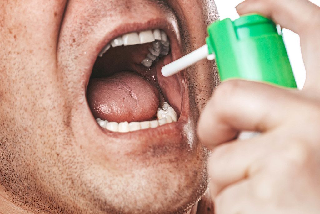 Close-up of a man with an open mouth sprays medical spray (Flip 2019)