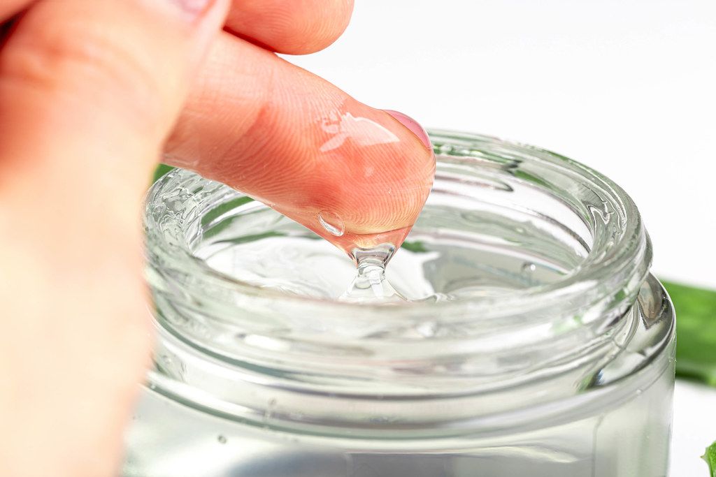 Close-up of a woman's hand and aloe Vera gel in a glass jar