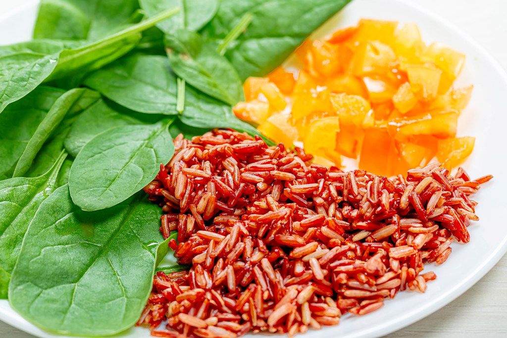 Close up of brown rice with spinach leaves and chopped bell peppers