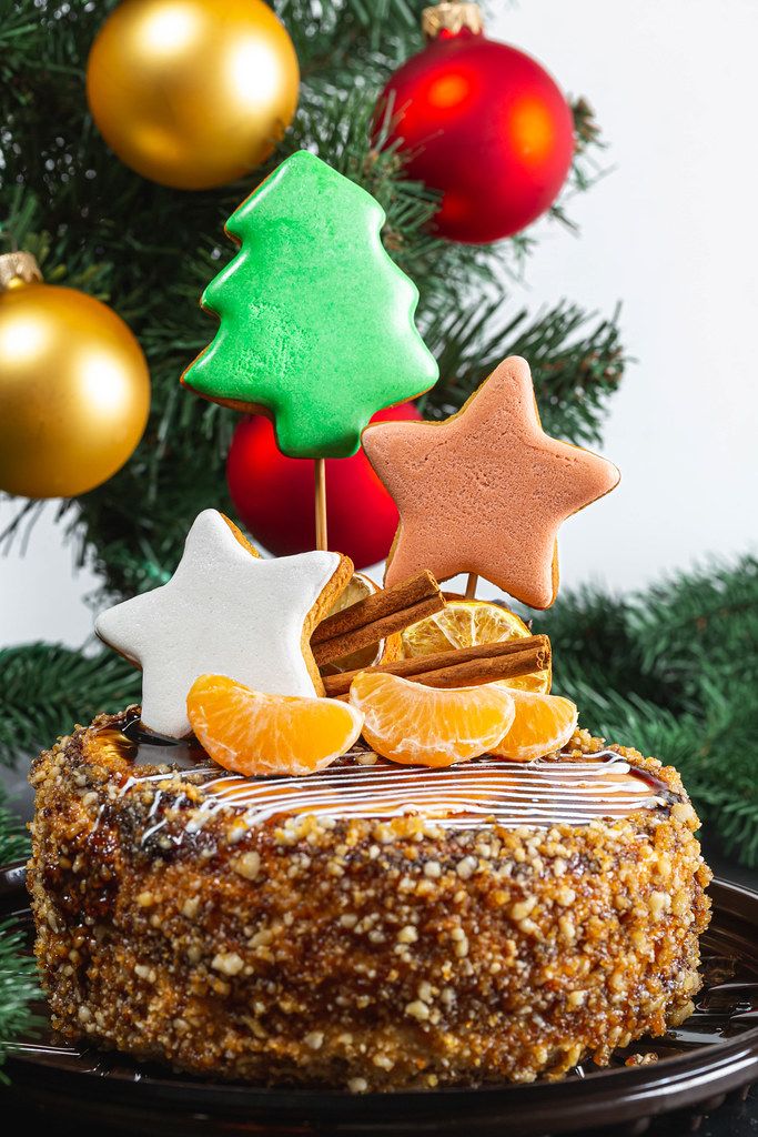 Close-up of Christmas cake with gingerbread and tangerines on the background of the Christmas tree