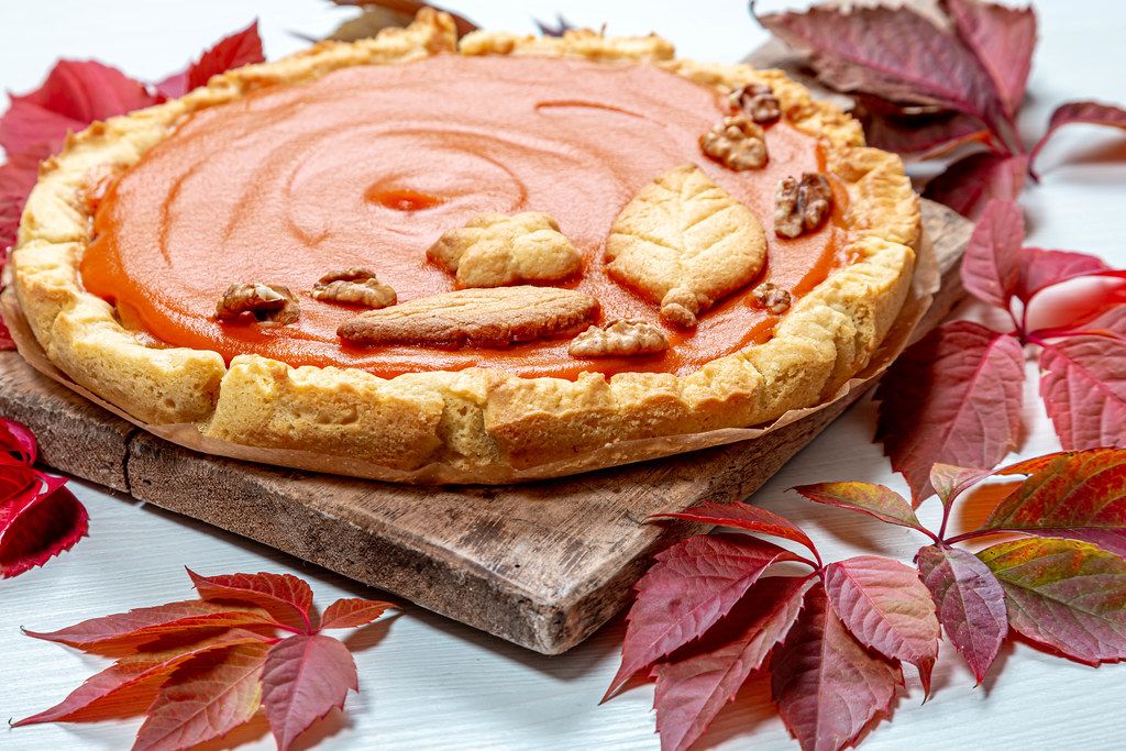 Close - up of homemade pumpkin pie on an old kitchen Board with colorful autumn leaves. The concept of the autumn holidays (Flip 2019)