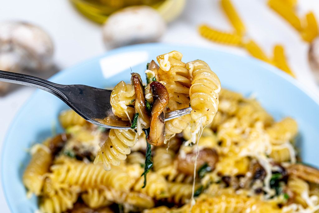 Close-up of pasta with mushrooms and cheese on a fork