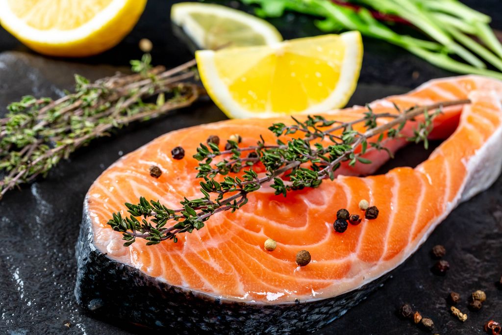 Close-up of raw salmon with fresh thyme and lemon slices