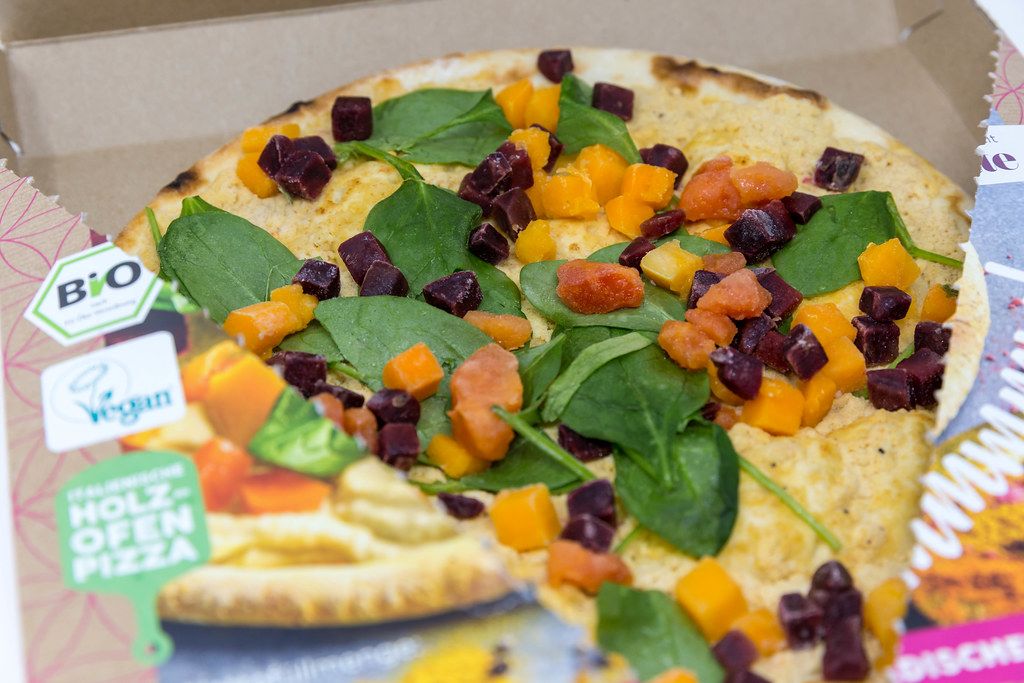 Close-up of the open package of Followfood organic vegan Yoga Pizza with spelt dough, hummus sauce, vegetables from sustainable farms. Cooked in wood-fired oven in Italy according to the tradition of pizza