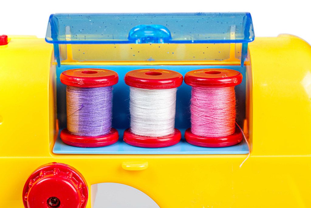 Close up of three spools of thread in a toy sewing machine