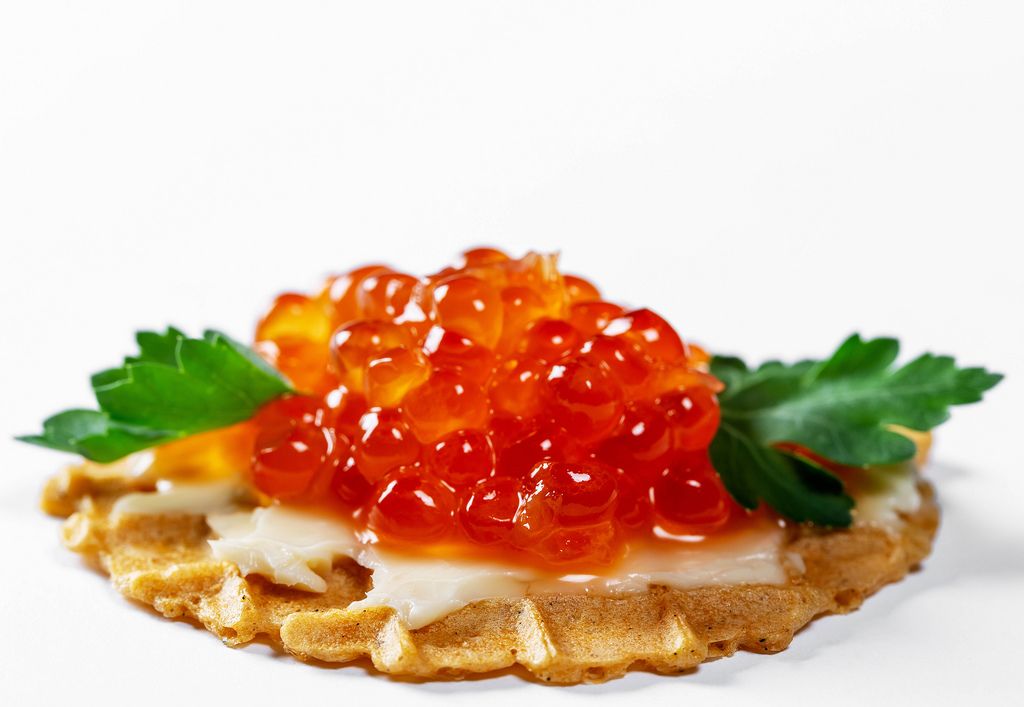 Close-up of waffle with red caviar, cheese and herbs