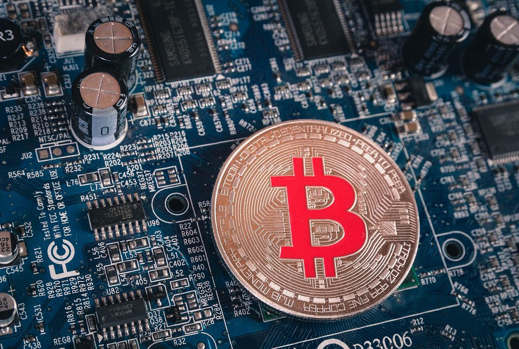 Close up photo of a silver Bitcoin on a computer mother board
