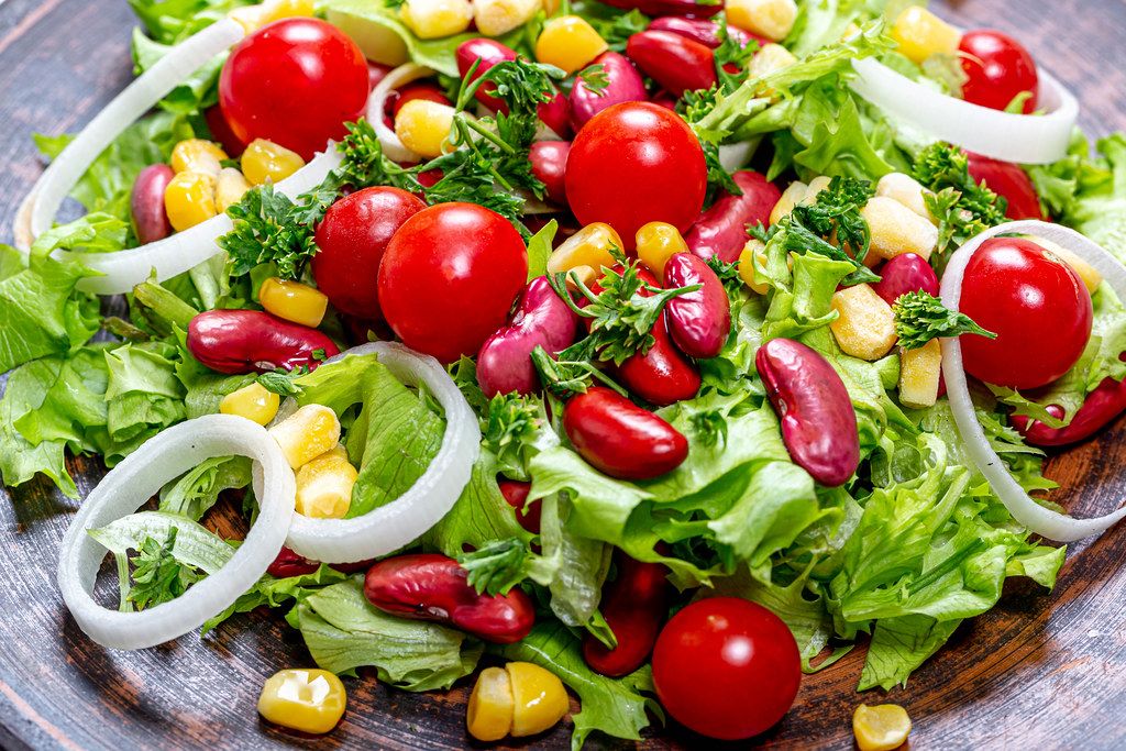 Close-up salad with beans, corn, tomatoes, lettuce, leeks and greens