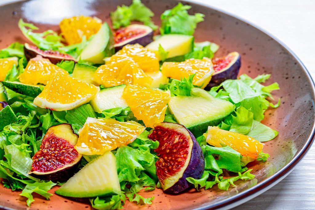 Close-up salad with lettuce, oranges, figs and mango on a plate