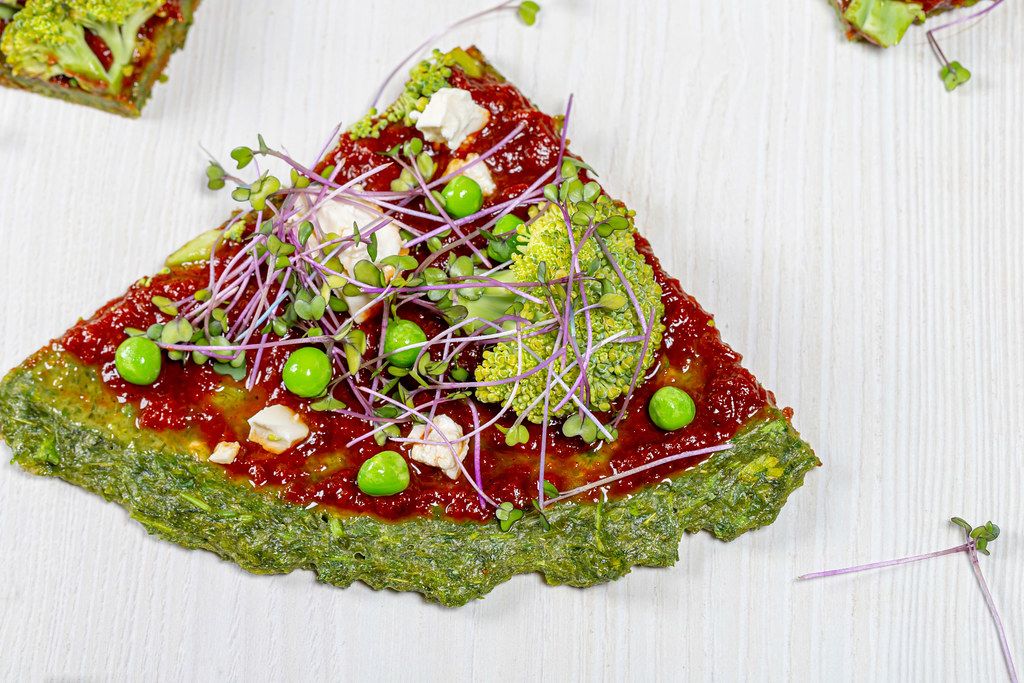 Close-up slices of vegetable pizza with micro-greens of cabbage, peas, corn and broccoli (Flip 2019)
