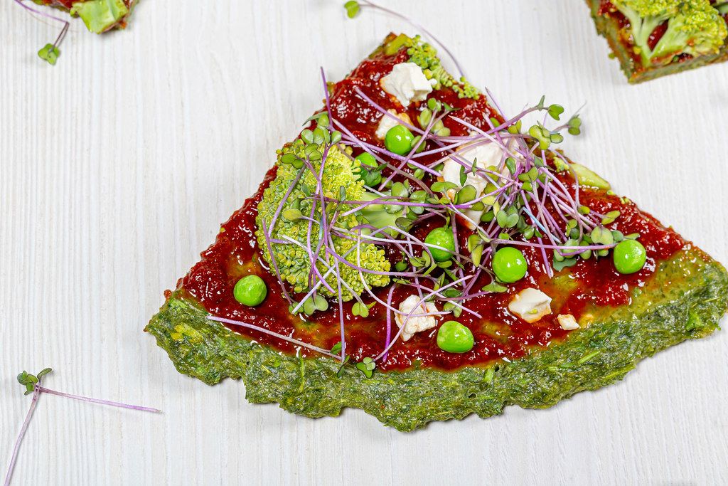 Close-up slices of vegetable pizza with micro-greens of cabbage, peas, corn and broccoli