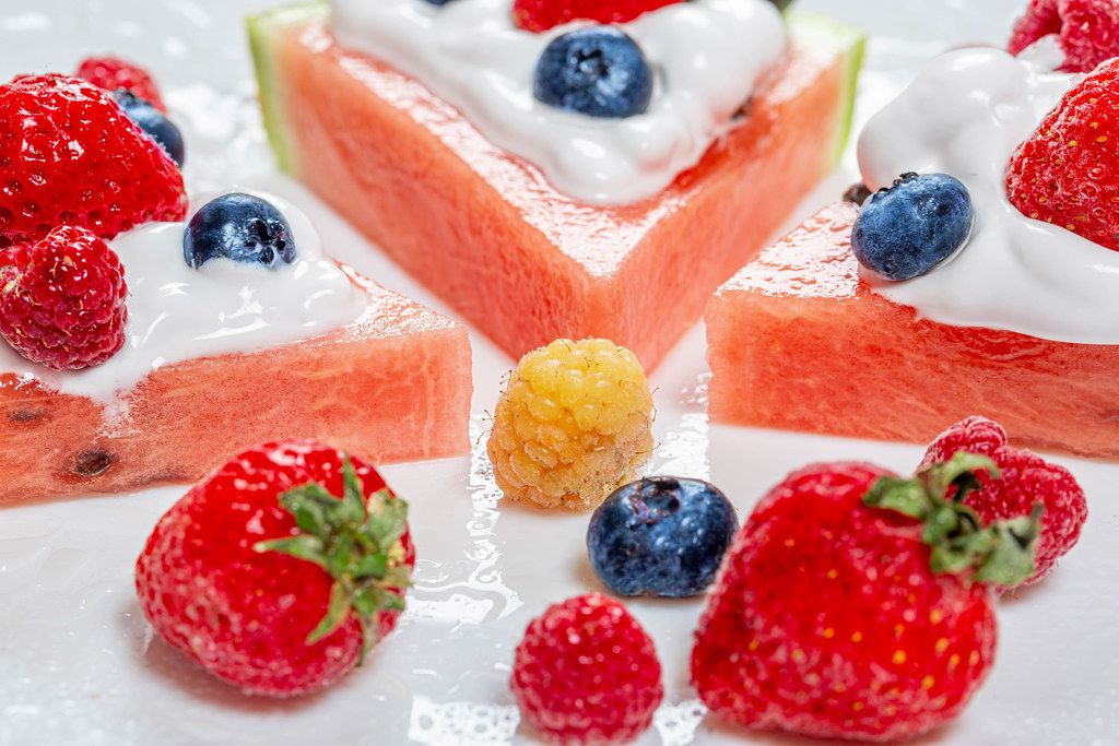 Close-up von Wassermelone mit frischen verschiedenen Beeren und Sahne ...