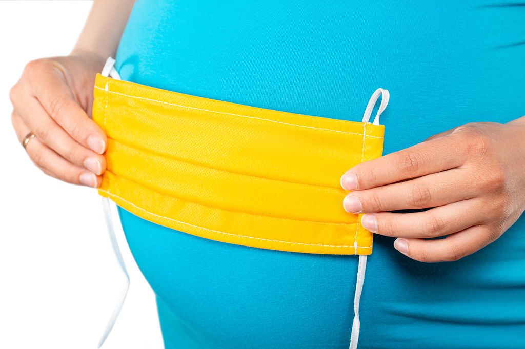 Close-up, yellow medical mask on a pregnant belly
