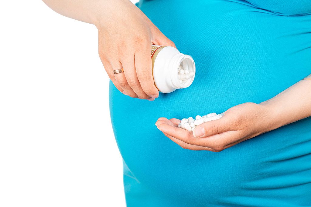 Closeup of pregnant woman's hands with pills. Consumption of pregnant calcium, vitamins