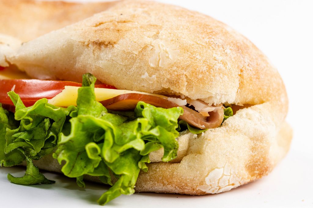 Closeup on Sandwich with Lettuce Cheese Ham and Tomato on white background