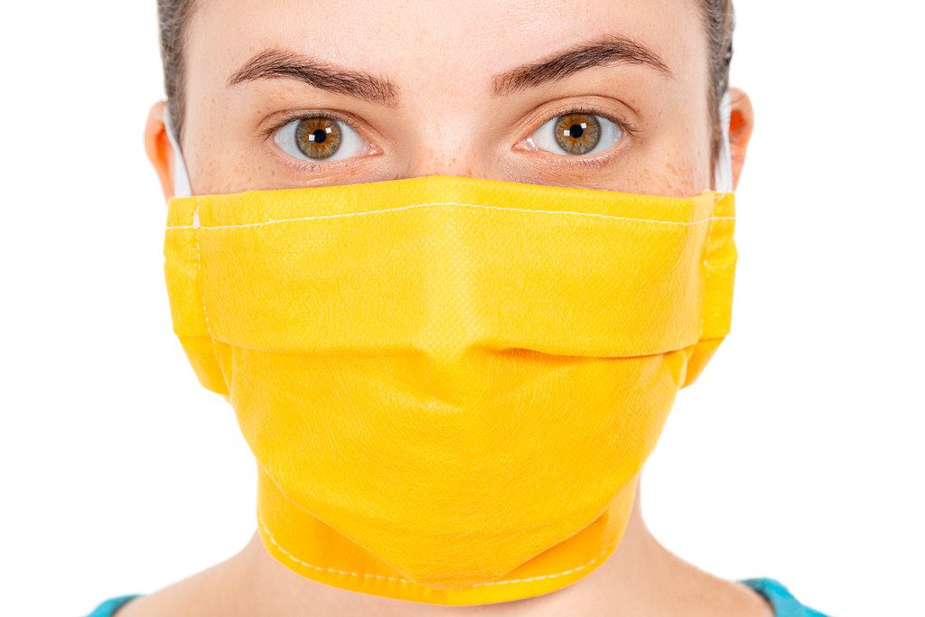 Closeup young girl face in yellow medical mask