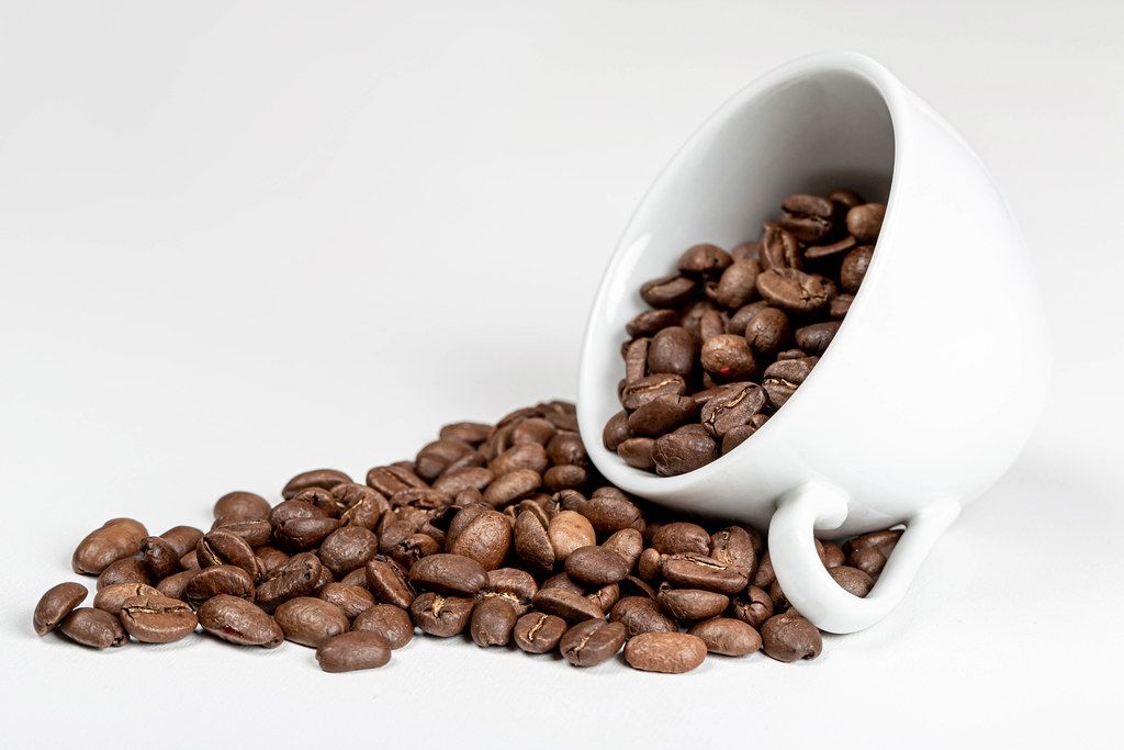 Coffee beans in coffee cup on white