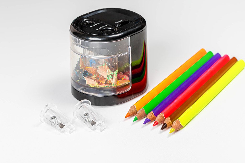 Colorful pencils and electric pencil sharpener on white background (Flip 2020)
