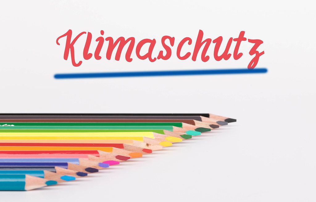 Colorful pencils on white background with Klimaschutz text