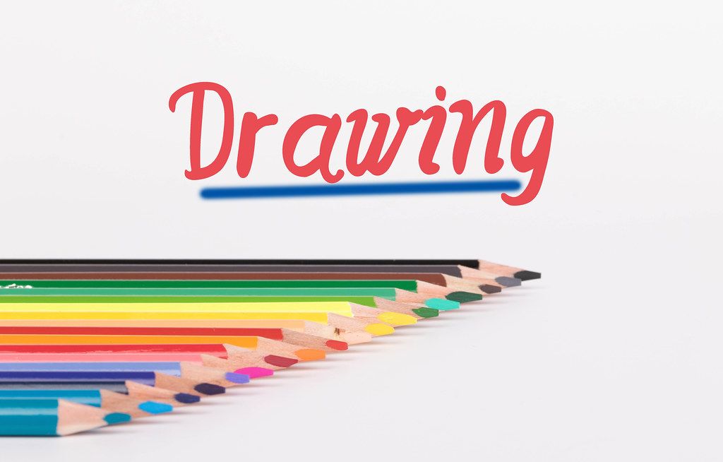 Colorful pencils on white background with text Drawing