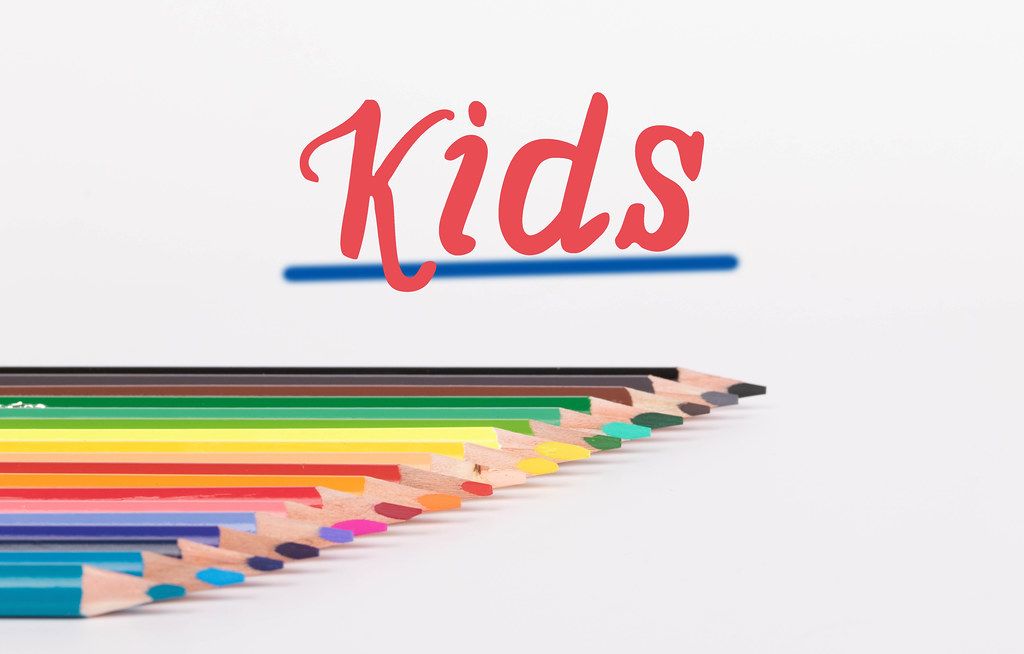 Colorful pencils on white background with text Kids