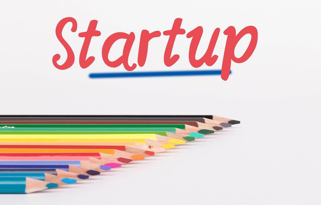 Colorful pencils on white background with text Startup