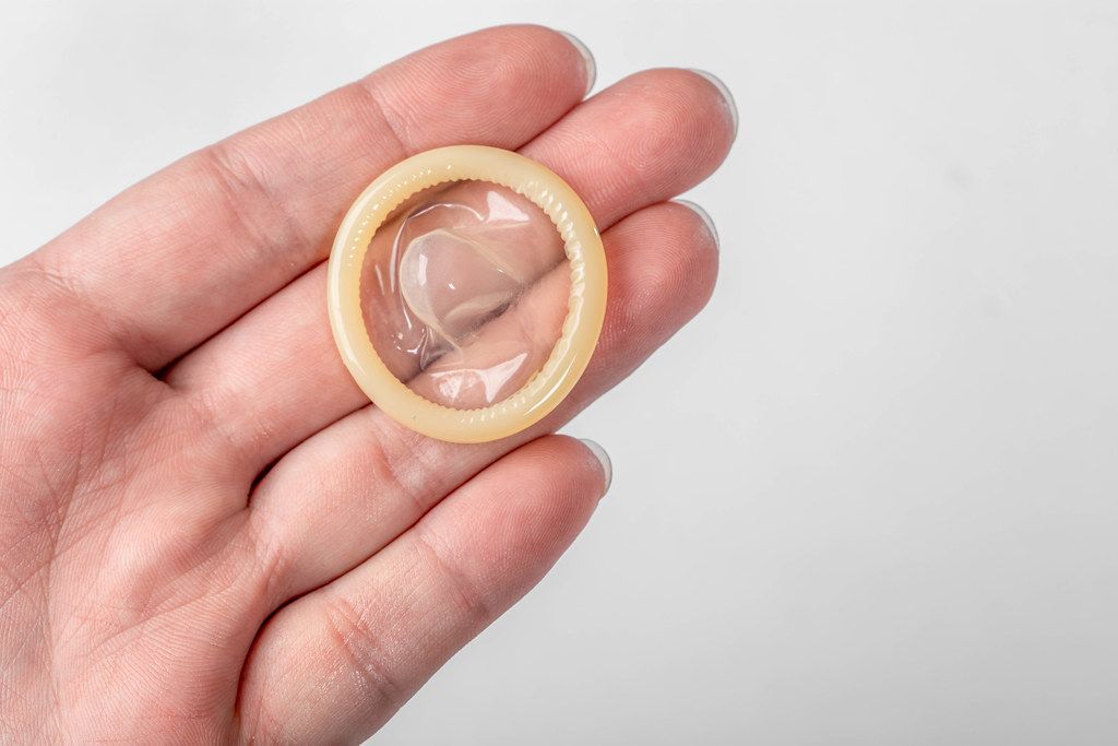 Condom without packaging on the hand of a man