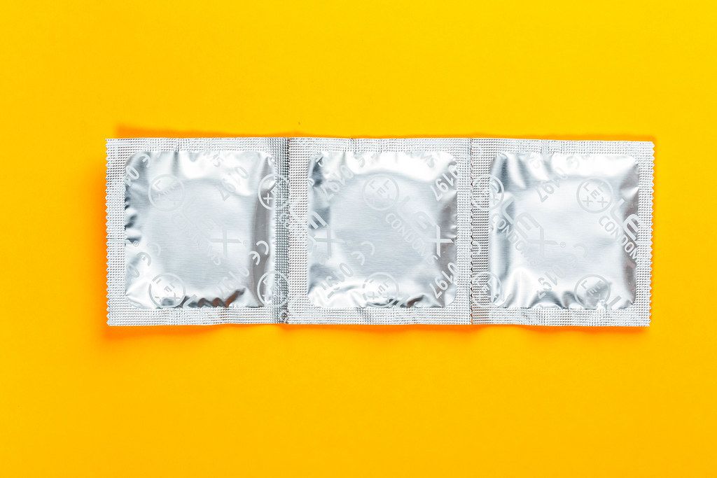 Condoms on a yellow background. Top view (Flip 2019)