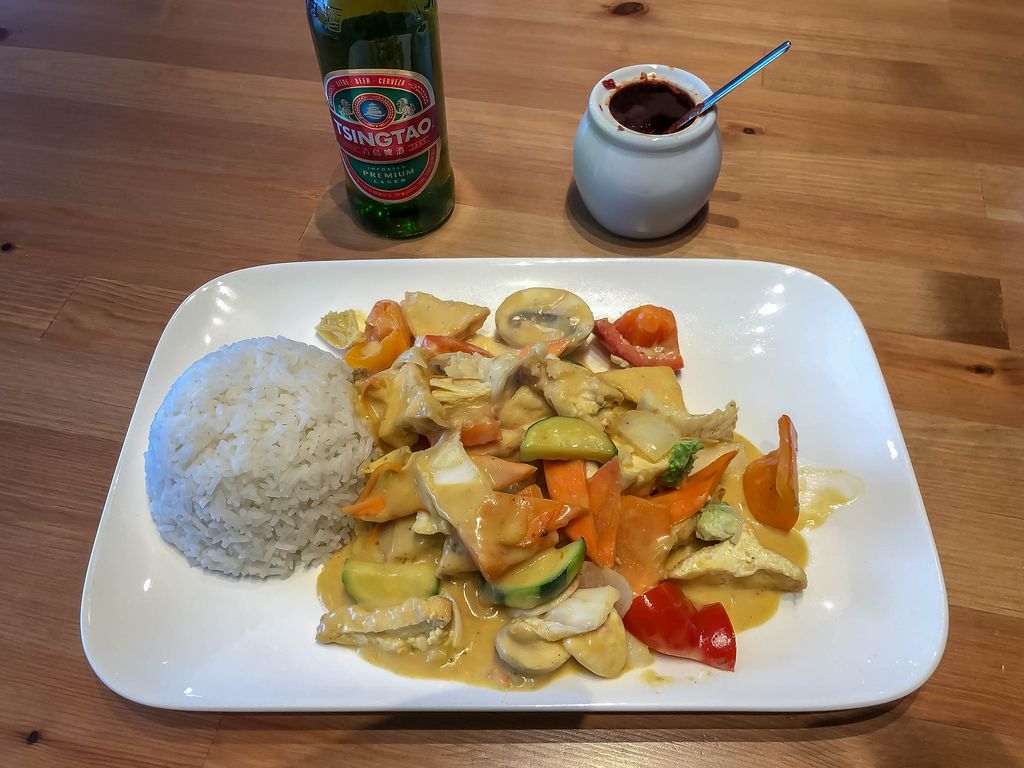 Curry mit Gemüse wie Zucchini, Champignons und Tomaten mit Reis und chinesischem Tsingao Bier