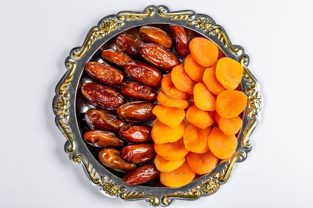 Dates and dried apricots on a tray on a white background. Top view (Flip 2019)