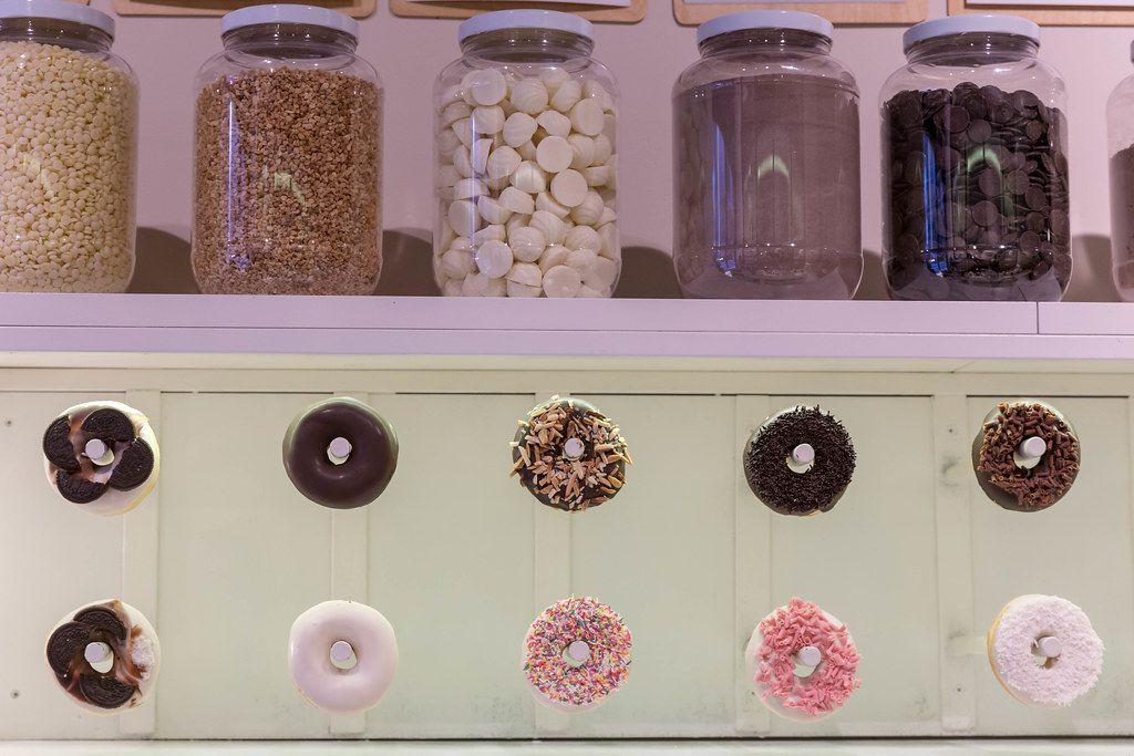 Dekoration mit Donut-Girlanden und gefüllten Einmachgläsern mit Nüssen und Schokolade, im Feinkostladen 