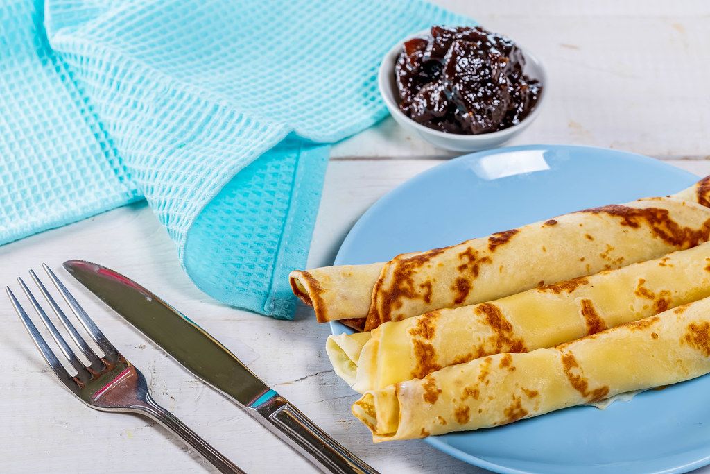 Delicious pancakes with jam, knife and fork