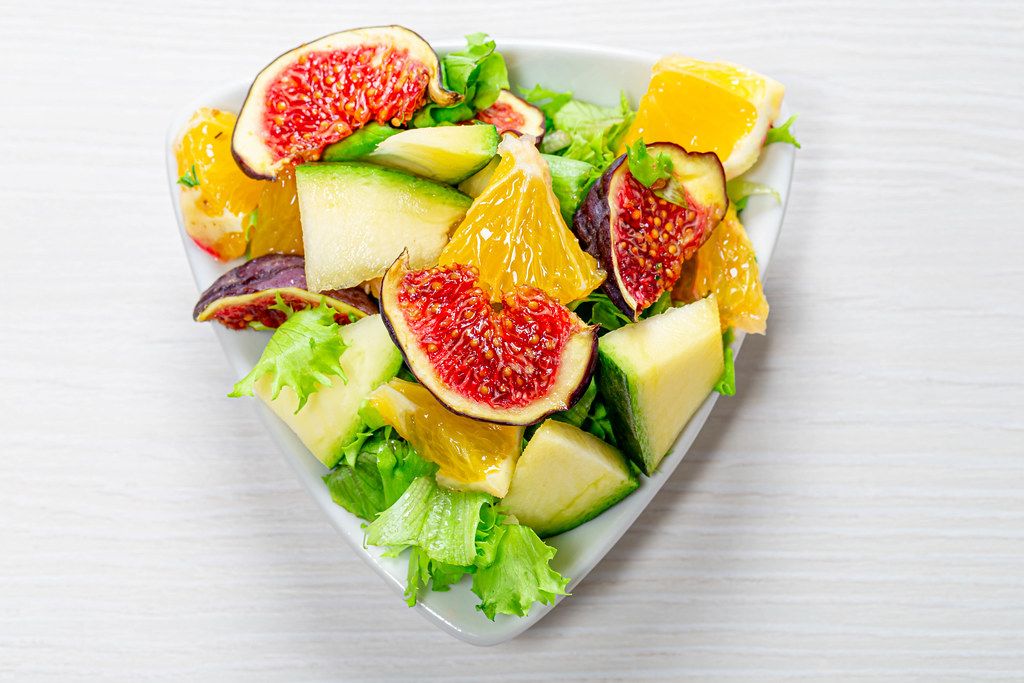 Delicious vegetarian salad with fresh vegetables and fruits in a triangular plate. Top view (Flip 2019)