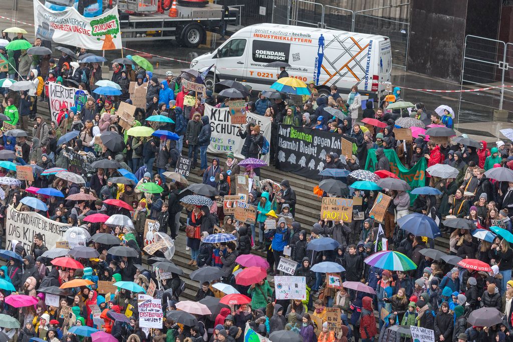Demonstrating youngsters with colorful signs and umbrellas at the Fridays For Future demonstration for the environment