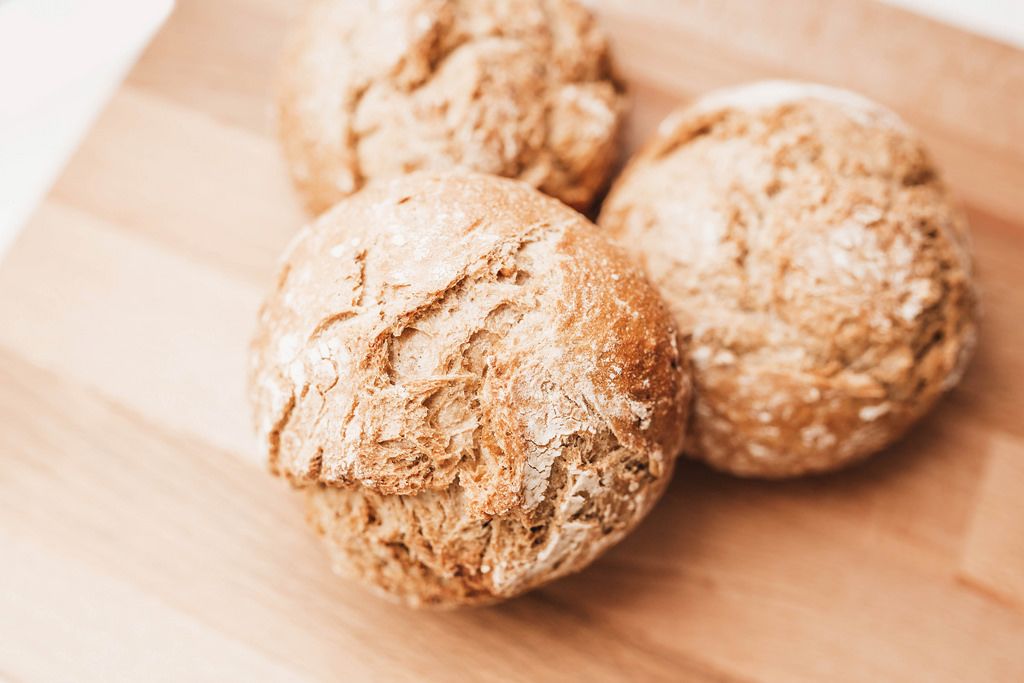 Detail of fresh baked wholemeal bread rolls on wooden board