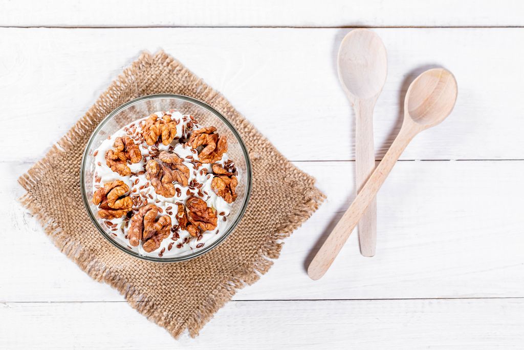 Diet cheese dessert with nuts and seeds on a white background with wooden spoons