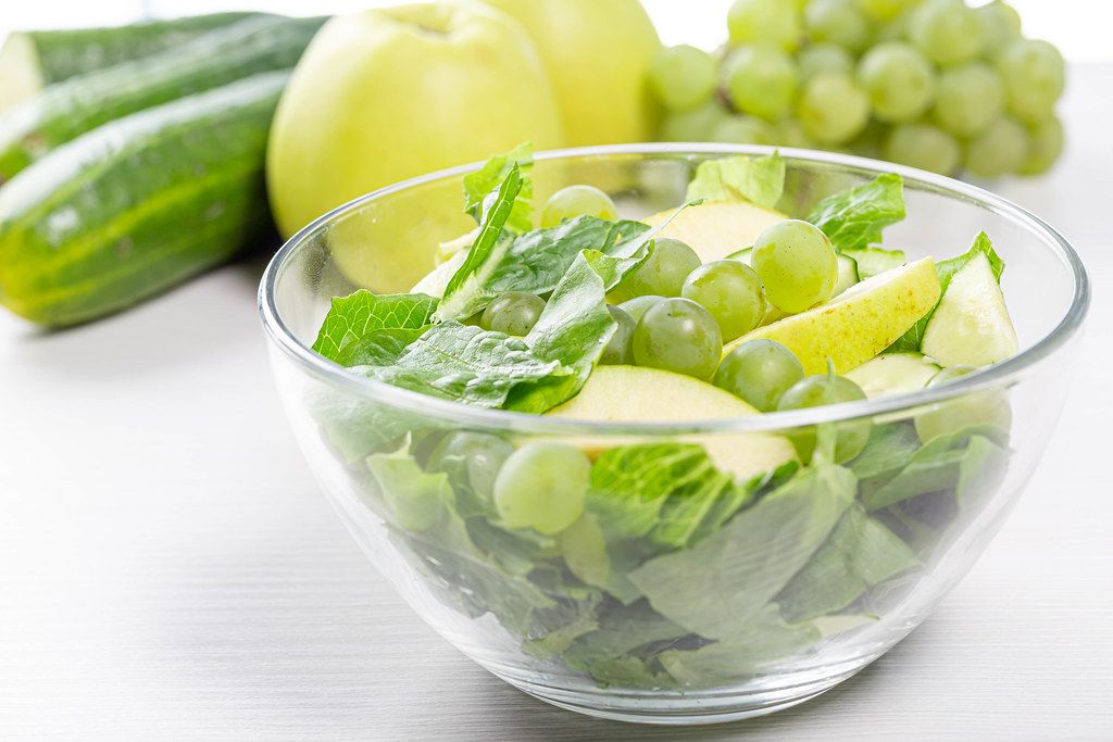 Diet salad with Romaine lettuce, cucumber, grapes and Apple in a glass bowl