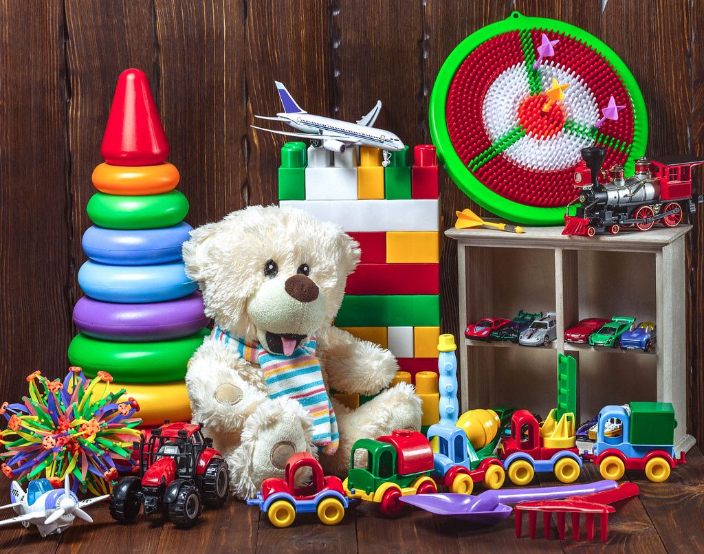 Different children's toys with a soft bear, cars, a plane, a train and a designer. Concept gifts, happy child