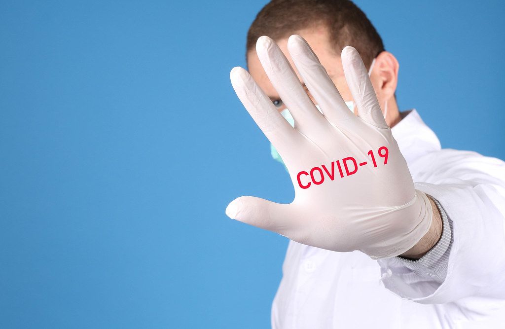 Doctor wearing medical gloves with COVID-19 text