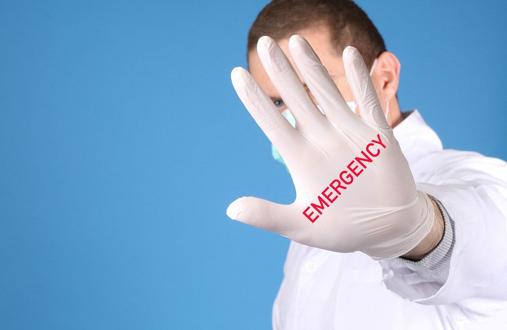 Doctor wearing medical gloves with Emergency text