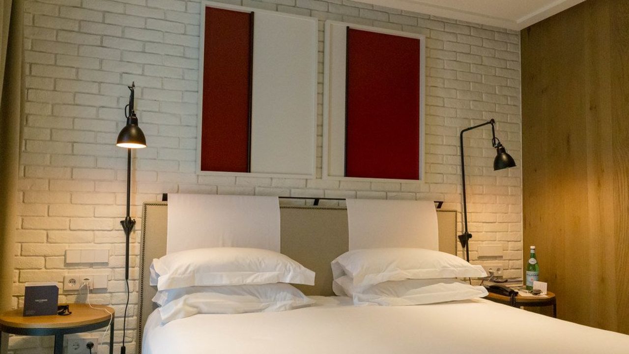 Double Bed With White Sheets And Brick Wall In The Hotel